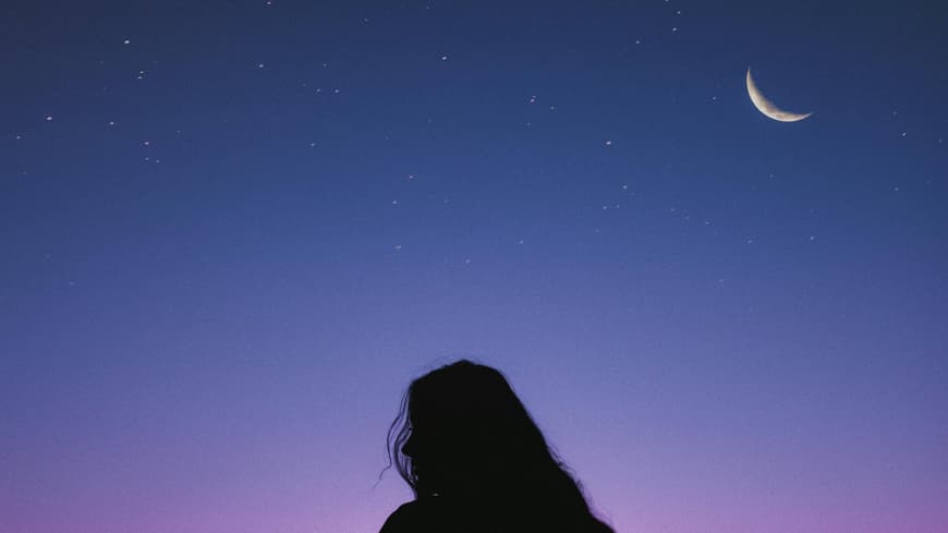 Diese 3 Sternzeichen können sich im Herbst auf ein richtiges Glow-up freuen. Frau unter lila Nachthimmel