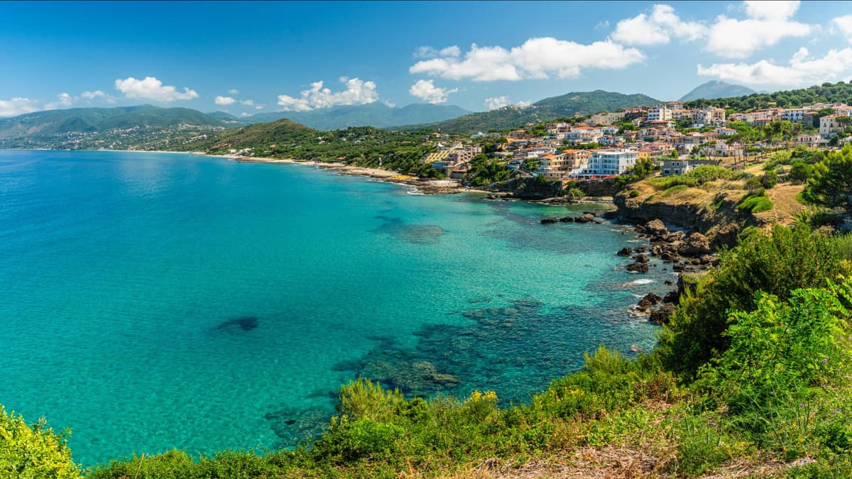 Der Blick aufs Wasser ist in Cilento besonder schön. Die Küste von Cilento mit Häusern, viel Grün und türkisblauem Meer.