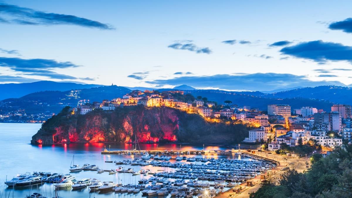 Beleuchtet ist Cilento noch viel schöner. Cilento in der Dämmerung mit beleuchteten Häusern und dem Hafen mit Schiffen und Yachten.