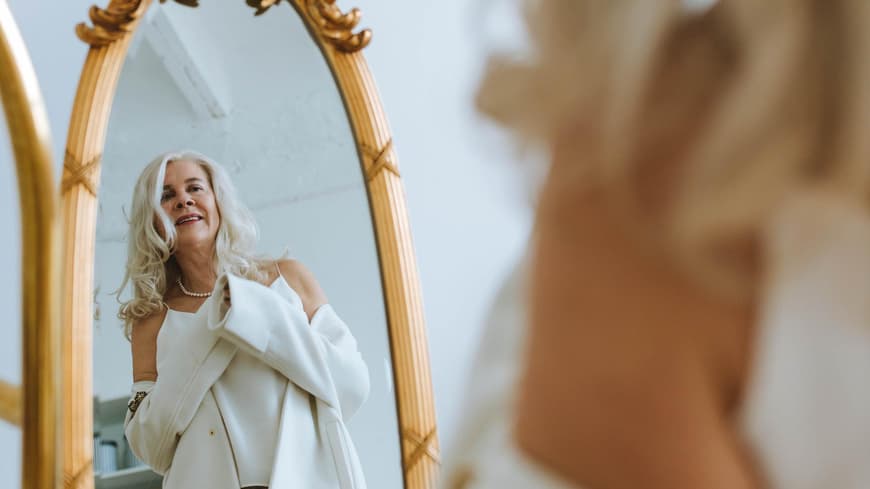 Positive Glaubenssätze können der Schlüssel zu einem besseren Selbstwert sein. Ältere Frau schaut in den Spiegel