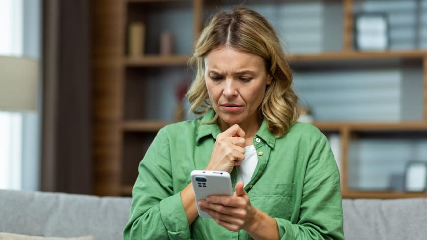 Er will keine Beziehung, aber meldet sich immer? Was dahinterstecken kann, liest du hier. Frau schaut verwundert auf ihr Smartphone
