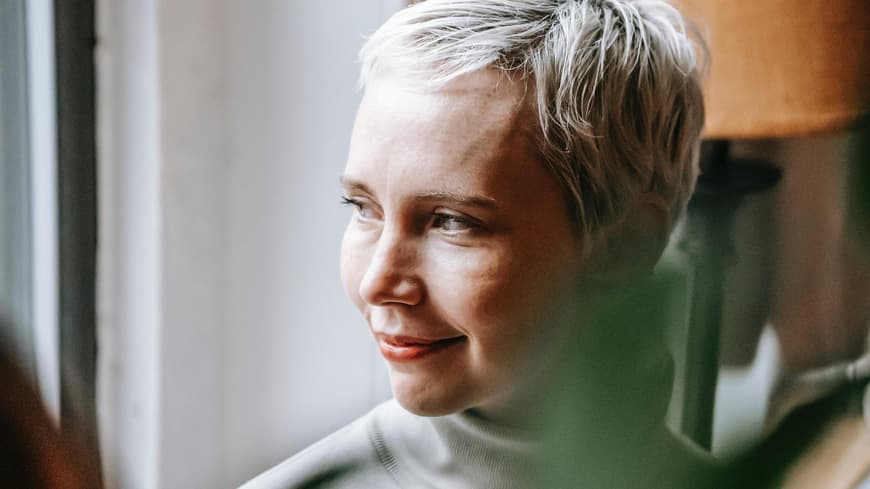 Fragen, die du dir vor dem Jahreswechsel stellen solltest. Frau schaut nachdenklich aus dem Fenster