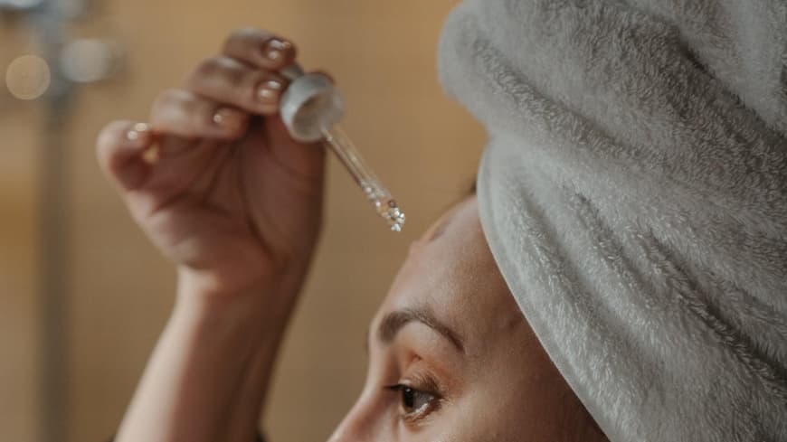 Frau trägt Gesichtsöl auf Frau trägt Gesichtsöl auf