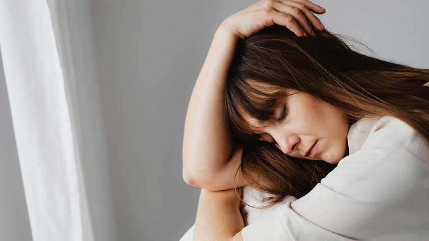 Macht Einsamkeit krank? Traurige Frau mi geschlossenen Augen