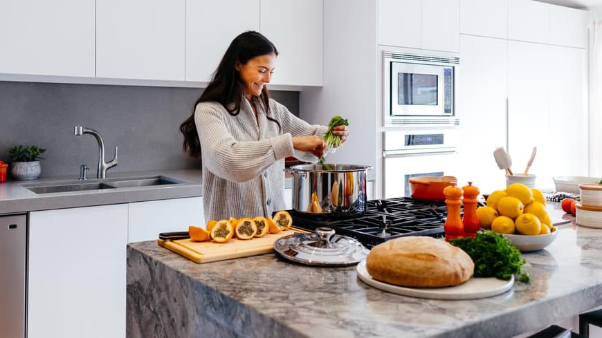 Rezepte mit viel Protein Frau im grauen Cardigan kocht in der Küche