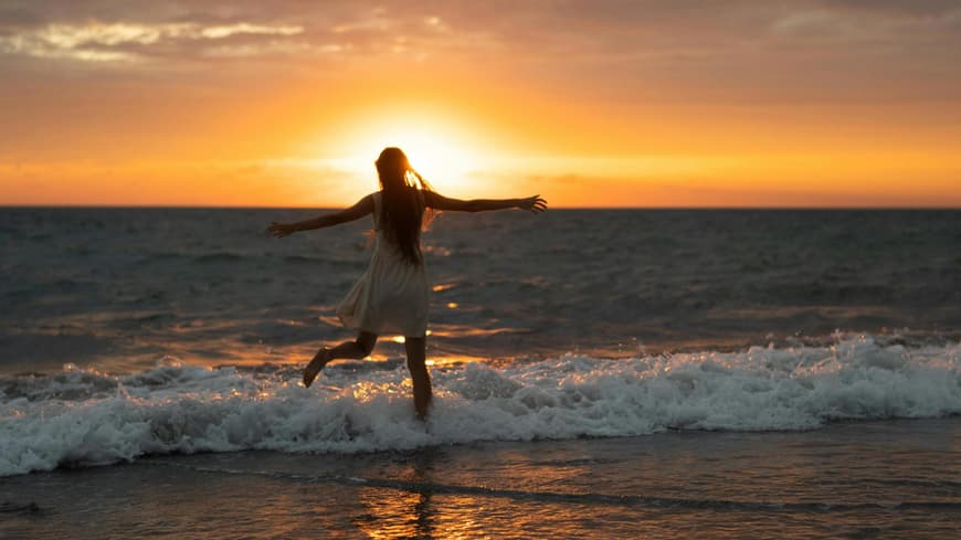 Monatshoroskop Glückstage Frau im Meer beim Sonnenuntergang