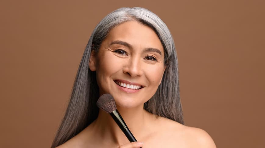 Welche Foundation für Frauen ab 50 besonders ideal ist, liest du hier. Ältere Frau mit Make-up Pinsel