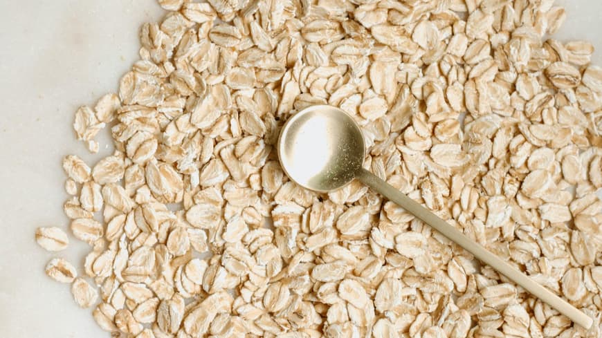 Abnehmen mit Haferflocken kann gelingen, wenn du ein paar Dinge beachtest. Haferflocken mit einem goldenen Löffel.