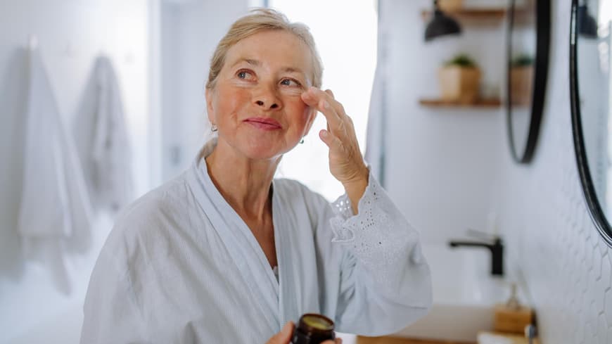 Augencremes mit Lichtschutzfaktor sind der ultimative Anti-Aging-Tipp. Ältere Frau trägt Augencreme mit Lichtschutzfaktor auf.