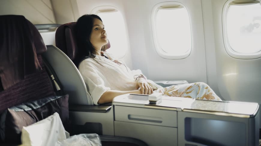Mit diesen Tipps erhöht sich die Wahrscheinlichkeit auf ein First-Class-Upgrade im Flugzeug. Frau in erster Klasse eines Flugzeuges