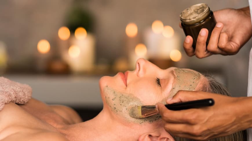 Die Leinsamen Maske fürs Gesicht soll wie Botox wirken. Frau liegt auf dem Rücken und bekommt eine Leinsamen Maske aufs Gesicht geschmiert.