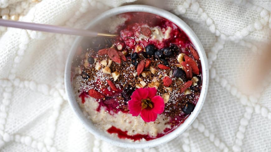 Porridge Toppings zum Abnehmen können Nüsse, Samen oder Früchte sein. Porridge in einer Schüssel mit verschiedenen bunten Toppings.