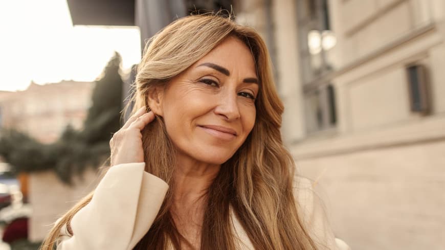 Welche Haarfarbe zu dir passt, erklärt ein Experte von John Frieda. Frau streicht Haare hinters Ohr