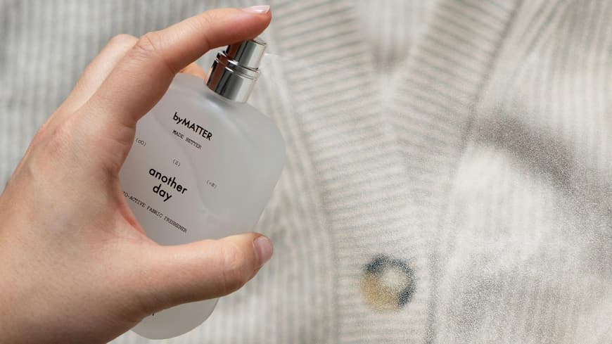 Frische Wäsche Parfum duftet sauber und rein. Jemand sprüht ein Parfum auf eine Strickjacke.