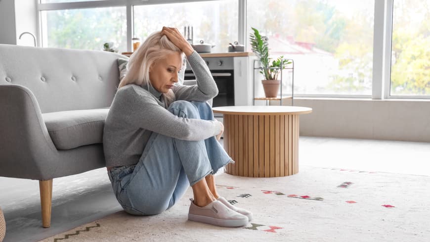 Wie man nach einer Enttäuschung in der Liebe wieder vertraut, erklärt ein Psychologe hier. Frau sitzt traurig am Boden