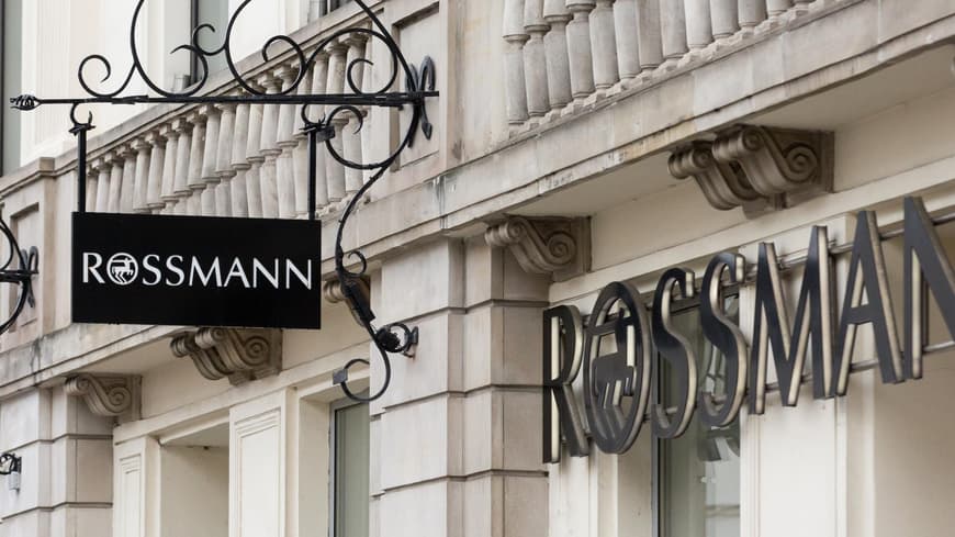 Jetzt reduziert: Dieses Sonnenfluid schützt und pflegt zugleich. Rossmann Filiale von draußen mit schwarzer Schrift und schwarzem Logo.