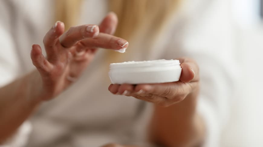 Diese Handcremes mit LSF schützen deine Hände vor vorzeitiger Hautalterung. Frau cremt ihre Hände ein.