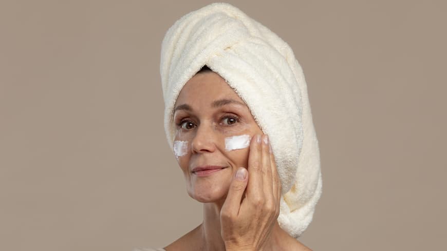 Welche Anti-Aging-Wirkstoffe bessere Alternativen zu Kollagen sind, verrät ein Dermatologe. Frau cremt Gesicht ein