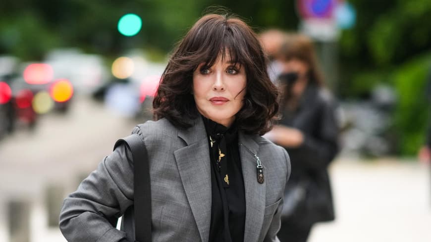 Frisuren mit Pony sehen ab 50 besonders gut aus. Frau mit dunklem Longbob und Pony trägt eine schwarze Bluse und einen grauen Blazer.