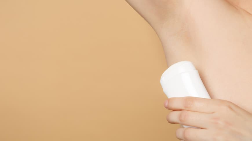 Deo gegen starkes Schwitzen kann im Alltag hilfreich sein. Ein Deoroller wird an eine Achsel gehalten.