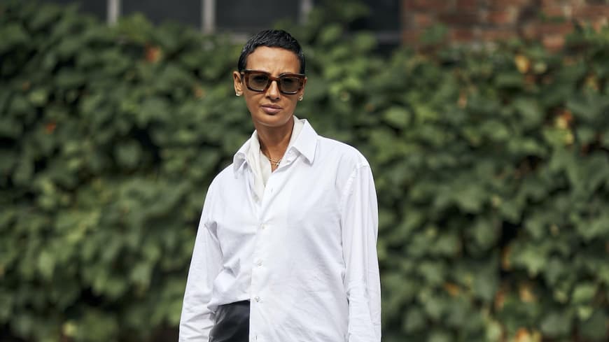 Kurzhaarfrisuren im Sommer sind stylish und praktisch. Frau mit kurzen Haaren trägt eine weiße Bluse, einen kurzen Lederrock und Loafer mit weißen Socken.