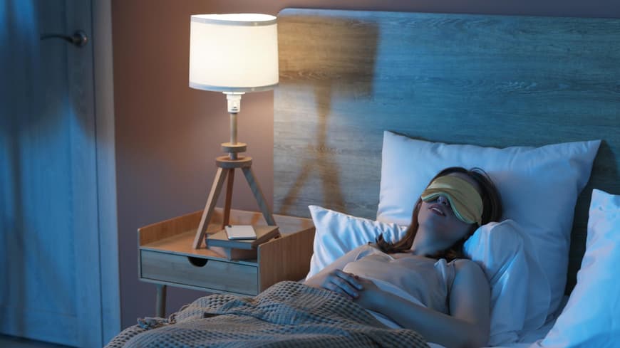 Frau schläft im Bett mit Schlafmaske Frau schläft im Bett mit Schlafmaske