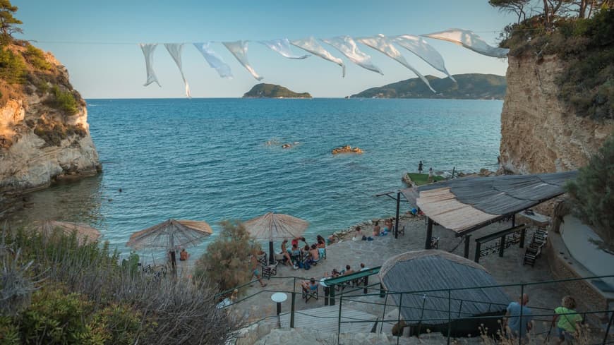 In Laganas erwarten dich tolle Beach Clubs zum Entspannen. Ein Beach Club an der Küste von Cameo Island mit ein paar Menschen.