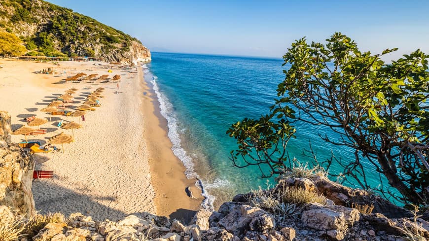 Himare in Albanien bietet tolle Urlaubsmöglichkeiten im Frühling. Ein Strand in Himare in Albanien mit türkisblauem Wasser und rauer Natur.