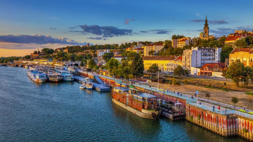 Belgrad ist eine Hafenstadt, die viel mehr zu bieten hat, als viele denken. Ein Blick über den Hafen von Belgrad mit Schiffen im Wasser und Häusern an Land, die von der Sonne beleuchtet werden.