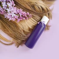 Das beste Drogerie Shampoo ist gar nicht so leicht zu finden. Haare einer Frau liegen mit Orchideen und einer lila Flasche auf einem rosafarbenen Hintergrund.