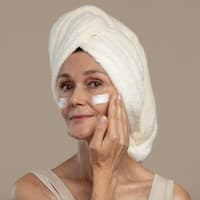 Welche Anti-Aging-Wirkstoffe bessere Alternativen zu Kollagen sind, verrät ein Dermatologe. Frau cremt Gesicht ein