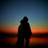 Welchen 4 Sternzeichen die intensivste Verbindung ihres Lebens bevorsteht? Das erfährst du hier. Ein Paar steht Rücken an Rücken vor dem Nachthimmel.