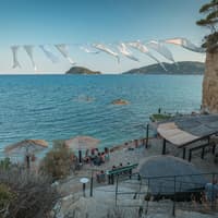 In Laganas erwarten dich tolle Beach Clubs zum Entspannen. Ein Beach Club an der Küste von Cameo Island mit ein paar Menschen.