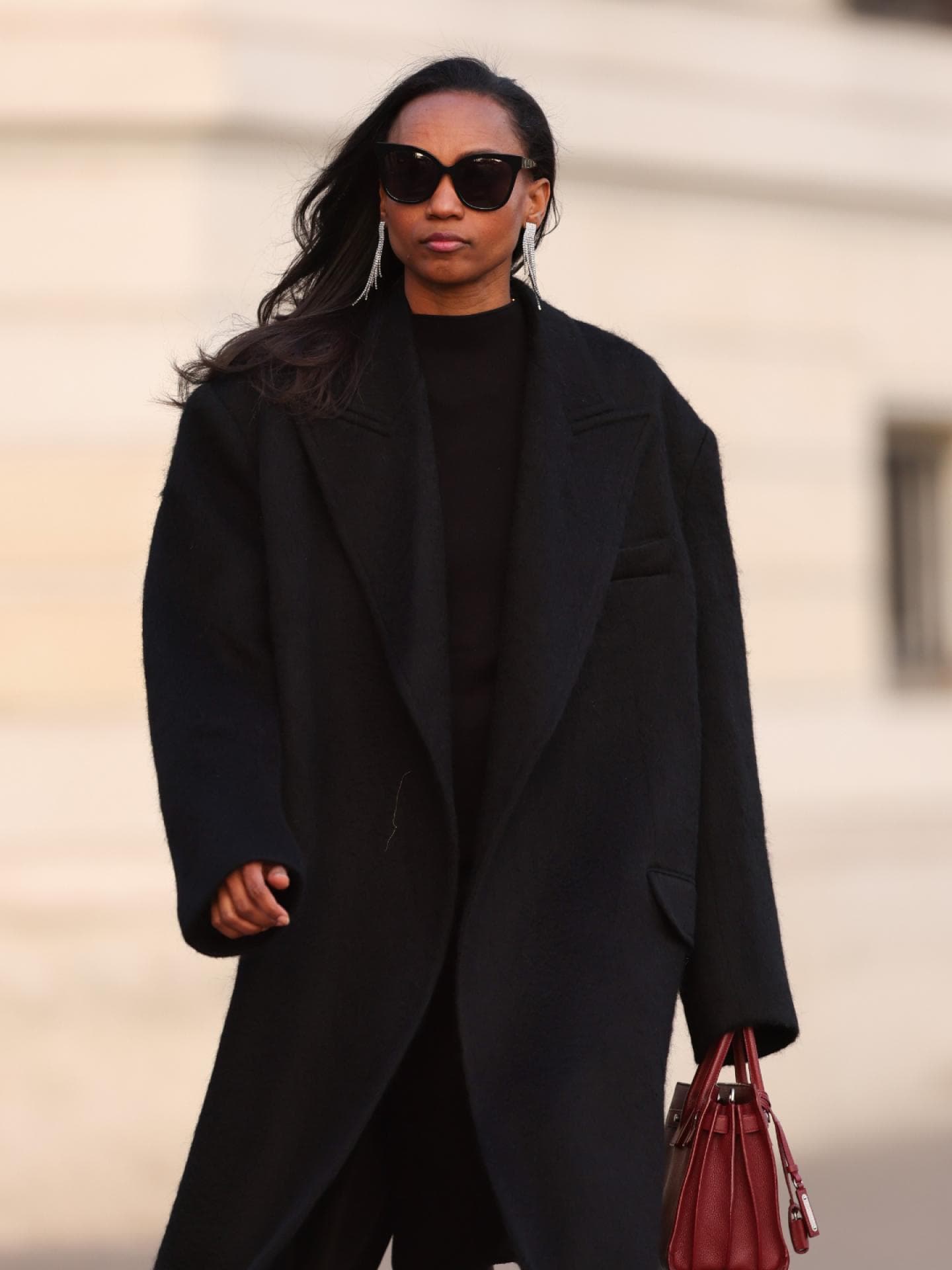 Frau trägt schwarzen Oversize-Mantel und rote Handtasche