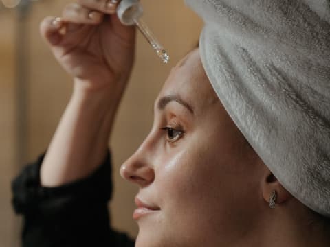 Frau trägt Gesichtsöl auf Frau trägt Gesichtsöl auf