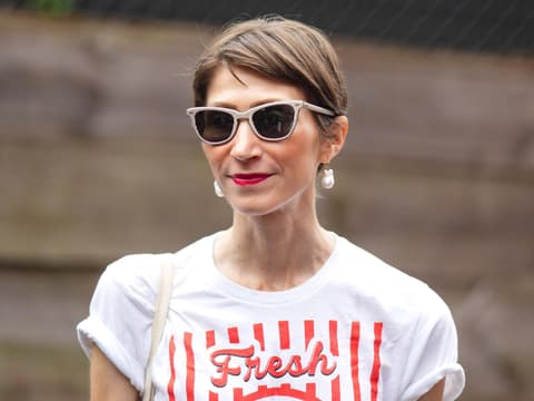 Kurzhaarfrisuren bei Frauen sind eine tolle Wahl. Frau mit braunhaarigem Kurzhaarschnitt, einer beigen Sonnenbrille und roten Lippen.