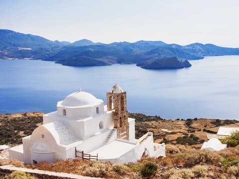 Die Insel Milos gilt als Geheimtipp in Griechenland. Eine griechische Kapelle mit dem Meer und Landschaft im Hintergrund.