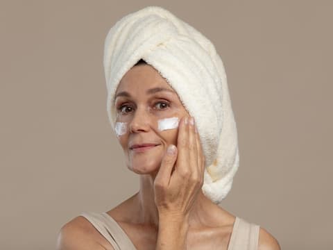 Welche Anti-Aging-Wirkstoffe bessere Alternativen zu Kollagen sind, verrät ein Dermatologe. Frau cremt Gesicht ein