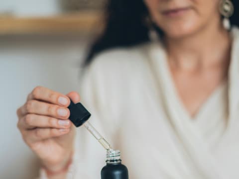 Welche Retinol-Alternativen eine ähnliche Wirkung haben, aber besser verträglich sind, erfährst du hier. Frau öffnet Hautpflege-Serum