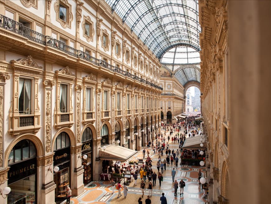 Mailand ist eine beliebte Metropole in Italien. Eine Plaza in Mailand mit einem durchsichtigen Kuppeldach und viel Stuck am Haus.