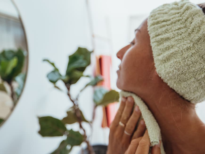 Wie oft du dein Handtuch fürs Gesicht wechseln solltest, erklärt eine Dermatologin. Frau trocknet ihr Gesicht ab
