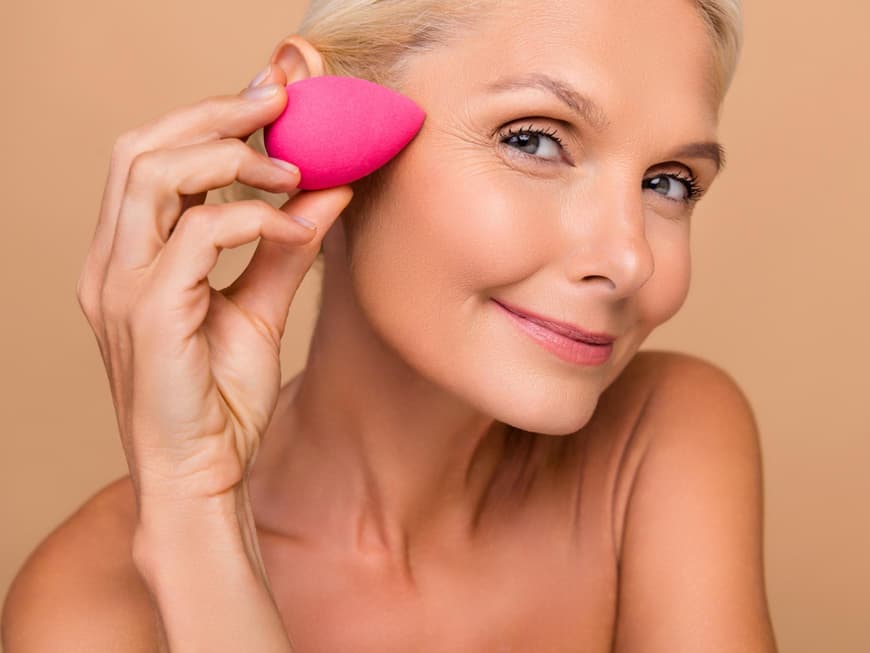 Ältere attraktive Frau mit Make-up-Schwämmchen Frau mit Verblender, um Concealer aufzutragen