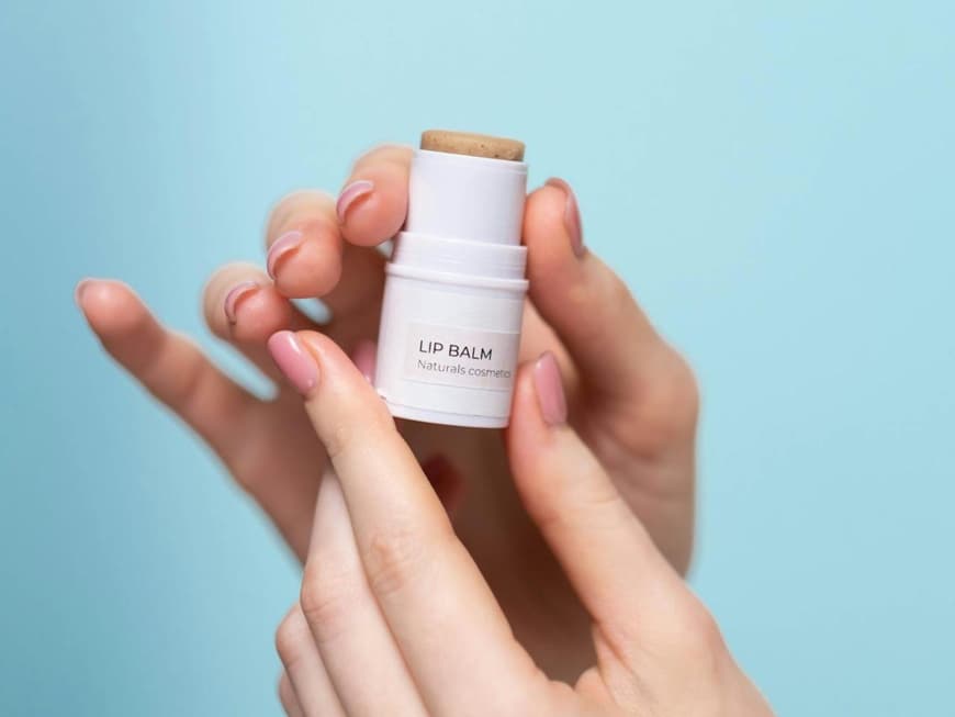 Peptide Lip Balms sind ein angesagter Beauty-Trend. Ein Lip Balm wird in der Hand vor einem hellblauen Hintergrund gehalten.