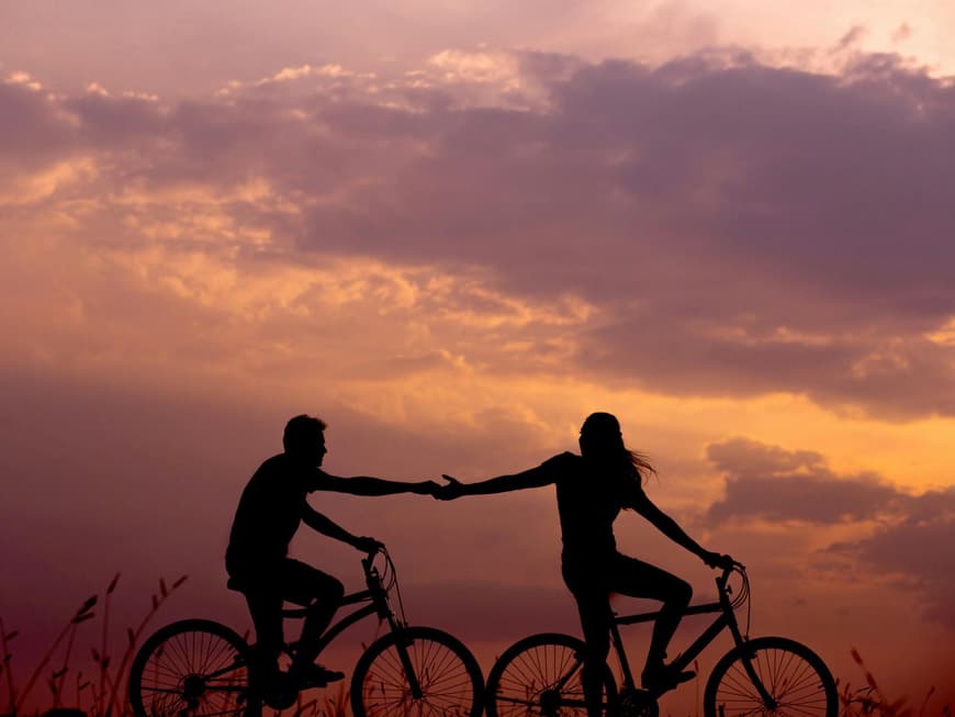 Das Liebeshoroskop für den Sommer 2025 hält einiges parat. Zwei Menschen als Schatten auf Fahrrädern voreinander und greifen mit den Händen zueinander.