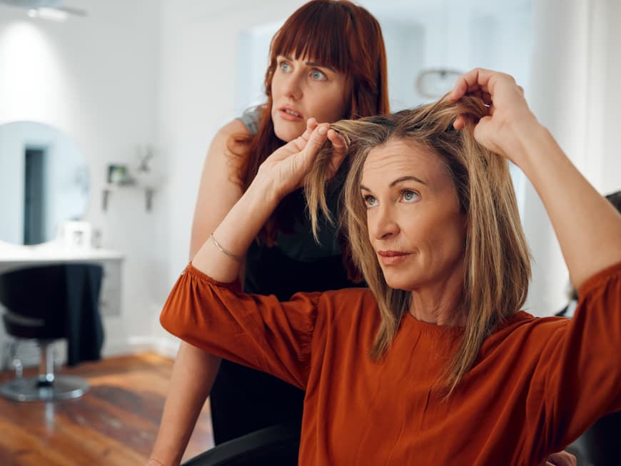 Wenn Hausmittel und Co. gegen den Grünstich nicht helfen – ab zum Profi. Frau beim Friseur