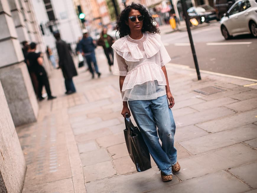 Eine Frau mit Baggy Jeans und weißer Bluse mit Volants