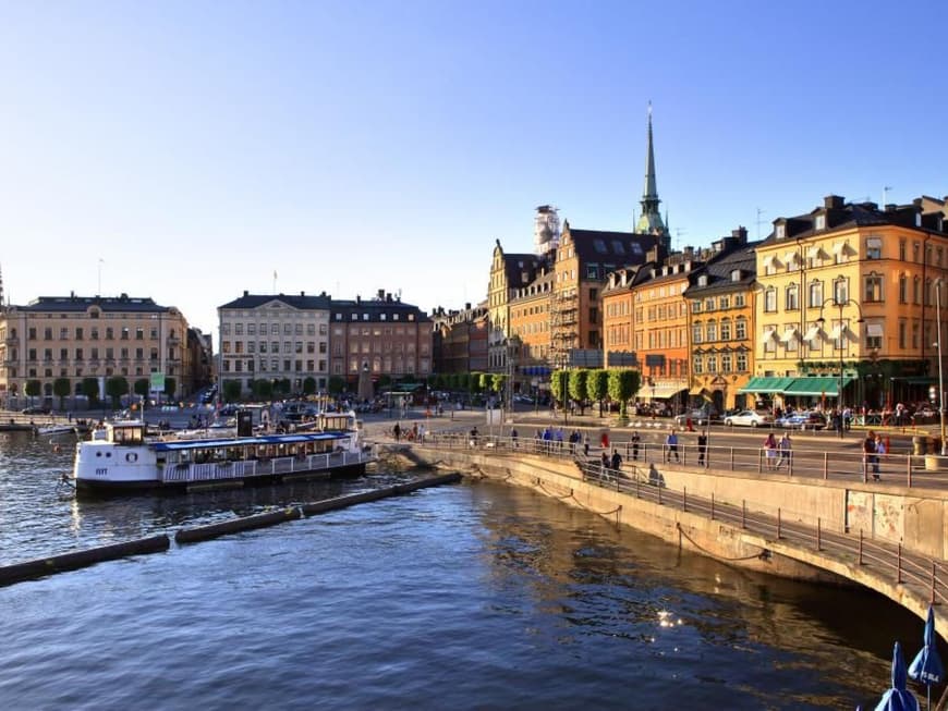 Stockholm eignet sich perfekt für einen Städtetrip in den Norden. Ein Blick auf eine bunte Häuserreihe am Hafen mit einer Straße mit einigen Menschen davor.